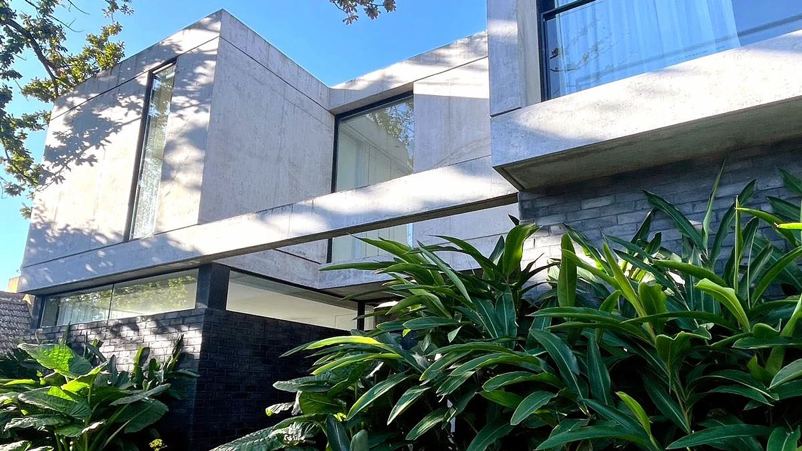 Fachada de hormigón y ladrillo de Casa Ro & Tic sobre el jardín, obra de Estudio TIC